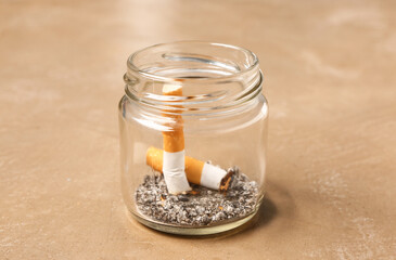 Jar with cigarettes and ash on grunge background, closeup. Lung cancer concept