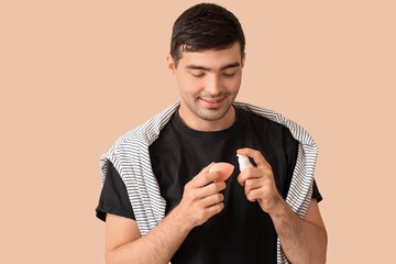 Male makeup artist with foundation and sponge on beige background