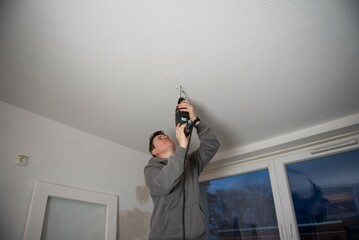 A person attaches a lamp to the ceiling