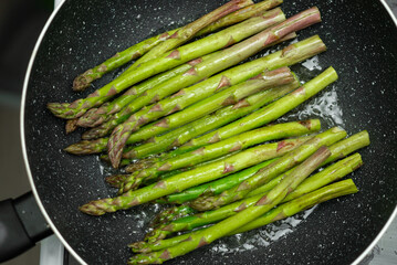 A pan of green asparagus is cooking in a pan