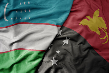 big waving national colorful flag of Papua New Guinea and national flag of uzbekistan.