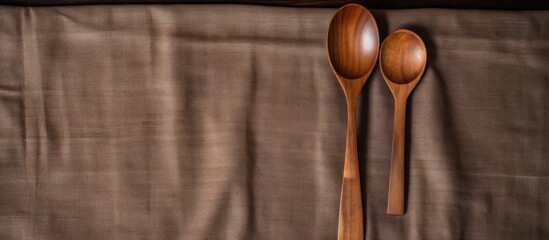 There are two wooden spoons and a spoon spoon laid out on a cloth surface