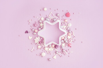 Star shaped cookie cutter with sweet colorful sprinkles scattered on lilac background