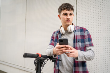 Young man caucasian teenager with electric kick push scooter in city