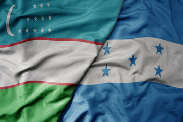 big waving national colorful flag of honduras and national flag of uzbekistan.