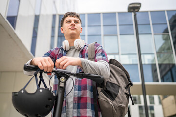 Young man caucasian teenager with electric kick push scooter in city