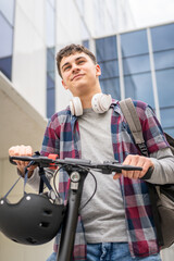 Young man caucasian teenager with electric kick push scooter in city