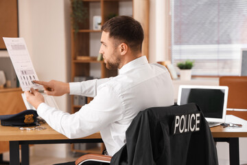 Male police officer with document in office