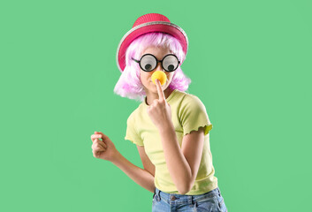 Funny little girl in disguise on green background. April Fools' Day celebration