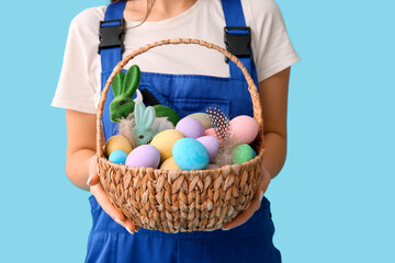 Fototapeta na wymiar Female worker with Easter eggs on blue background, closeup