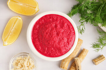 Horseradish sauce with beet in bowl and ground horseradish with lemon on white background. Top view