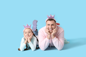 Father and his daughter in princess costumes on blue background