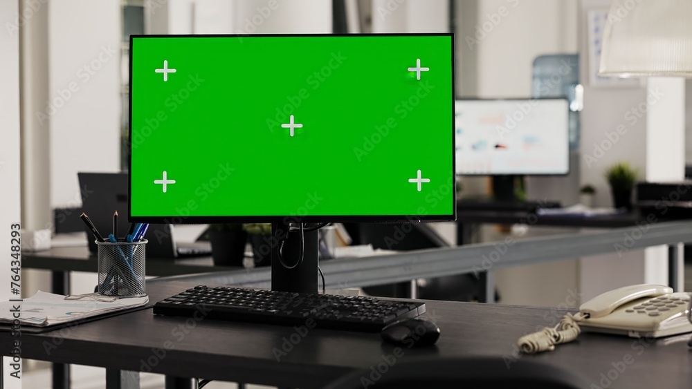 Poster empty desk with computer shows greenscreen on monitor, running blank mockup copyspace in business of