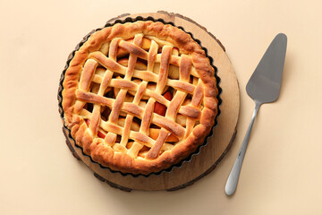 Wooden tray with tasty homemade apple pie and spatula on beige background