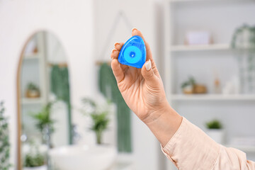 Female hand with dental floss in bathroom at home