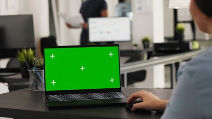 Analyst reviews greenscreen display on laptop, working on small business operations and tasks....