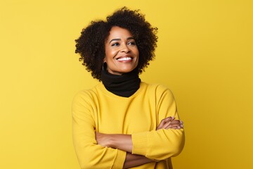 Obraz na płótnie Canvas Smiling african american woman in yellow sweater and scarf on yellow background