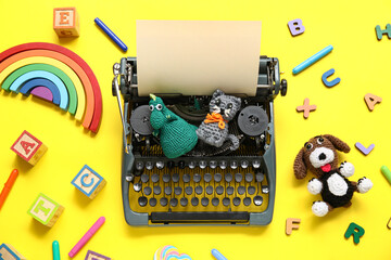 Composition with vintage typewriter and knitted toys on yellow background