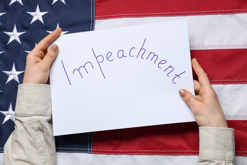 Woman holding IMPEACHMENT picket poster against USA flag background