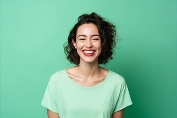 Portrait of a beautiful young woman laughing and looking at camera on a green background