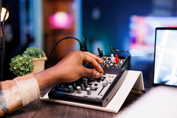 Detailed view of black person adjusting sound mixer to achieve high-quality recording during the...
