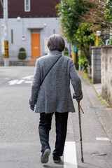 杖をついて歩く老人の後ろ姿