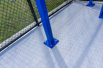 View of typical nondescript high school baseball softball dugout with concrete floor, chain link...