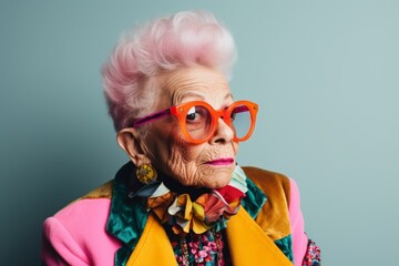 Portrait of an elderly woman with pink hair and glasses. Studio shot.