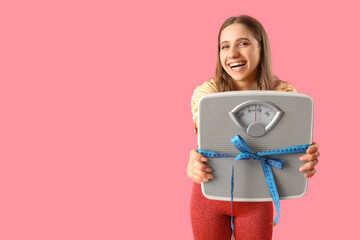 Pretty young woman in sportswear with scales and measuring tape on pink background. Weight loss...