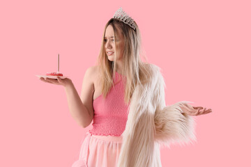 Young woman with hangover and doughnut after Birthday party on pink background