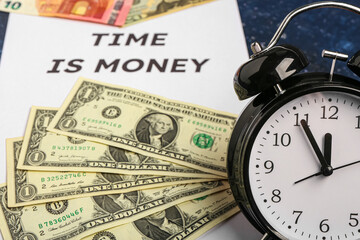 Paper with text TIME IS MONEY, alarm clock and dollar banknotes on blue grunge background
