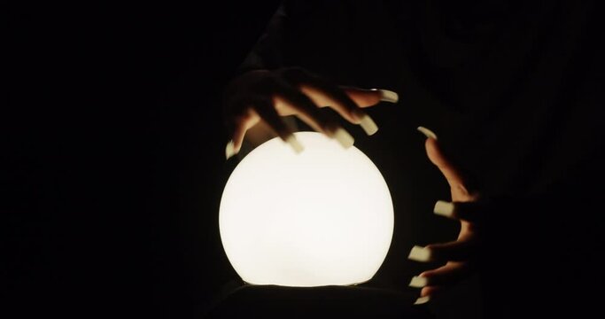 Hand of magician or fortune teller above glass ball. Oracle is predicting the future.
