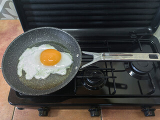 Big goose egg frying in a pan on a gas stove