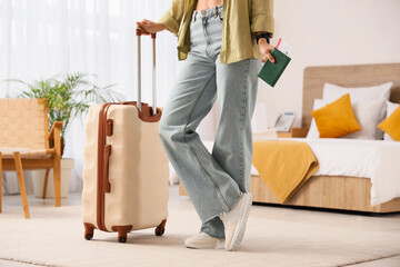 Female tourist with passport and suitcase in hotel room