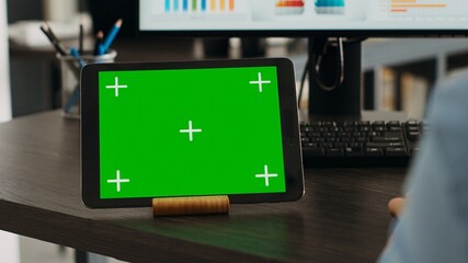 Startup specialist looks at digital tablet with greenscreen, using gadget with blank chromakey template. Person working at desk with isolated mockup copyspace, checking marketing data. Close up.