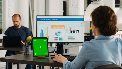 Business person using pc at workstation, having greenscreen display template on tablet in front of her. Manager planning startup operations and checking isolated mockup layout on device.