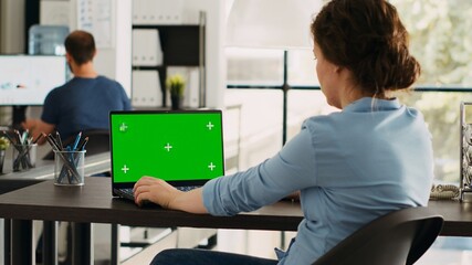 Businesswoman looks at greenscreen on laptop, checking pc at desk and working on startup...
