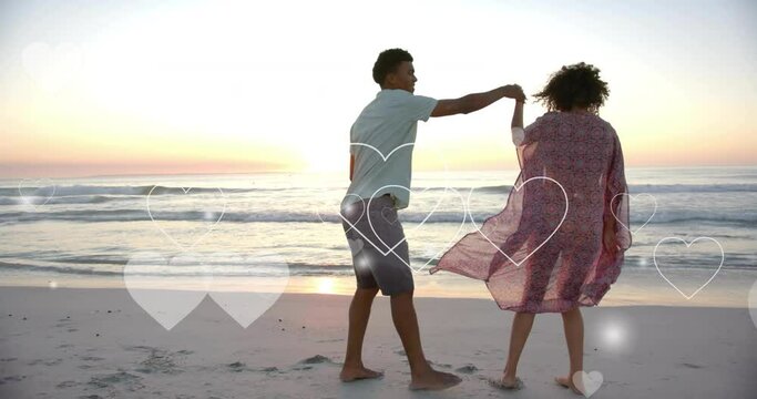 Animation of hearts moving over diverse couple in love on beach in summer