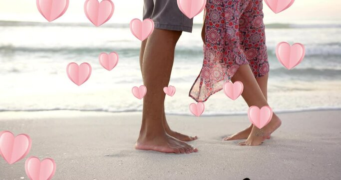 Animation of hearts moving over legs of diverse couple in love on beach in summer