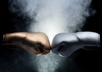 Two Boxing Glove in silver and gold punch hit together. Business challenge fighting concept. Smoke at back, black background isolated