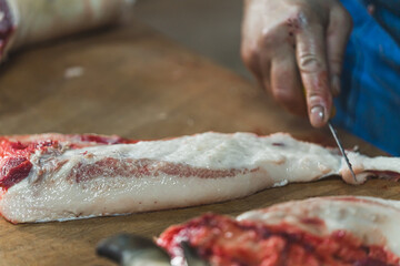 a butcher cutting pig meat into slices on the table, butchers shop, cutting pork. High quality photo