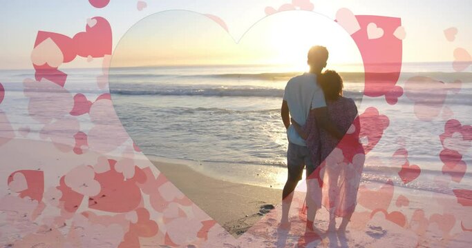 Animation of hearts moving over diverse couple in love embracing on beach in summer