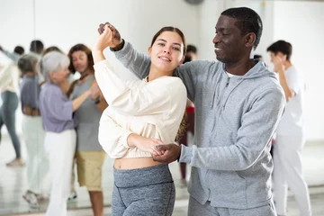 Photo sur Plexiglas École de danse Portrait of young girl and adult African American man practicing in modern choreography studio, dancing slow ballroom dances in pair..