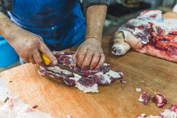 Butcher cuts freshly slaughtered meat of pork for sale and further processing. High quality photo