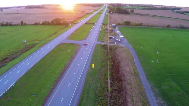 Aerial Forward Shot Of Cars Moving On Roads In Agricultural Field Against Clear Sky During Sunset - Buckner, California