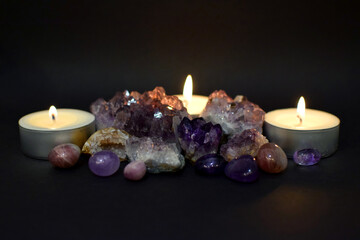 Beautiful purple druzy with amethyst crystals and burning candles in the dark. Selective focus.