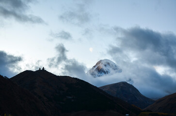 View from Stepantsminda to silhouette of the Gergeti Monastery against the backdrop of majestic...