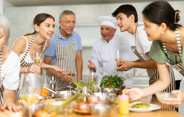 Group of different people drinking wine and talking after cooking master class