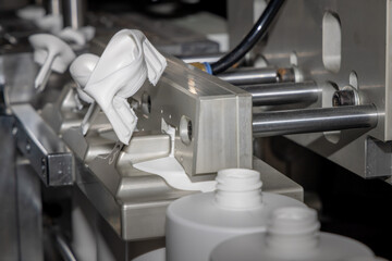 Automated production line for casting white plastic bottles. White plastic bottles on a production line. Molding of white plastic bottles. Liquid packaging