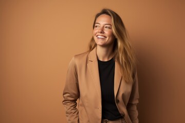 Happy young businesswoman in beige jacket on beige background.